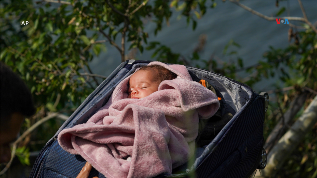  Migrantes cruzan el Río Bravo hacia Estados Unidos con un bebé en una maleta, visto desde Matamoros, México, el 10 de mayo de 2023.   
