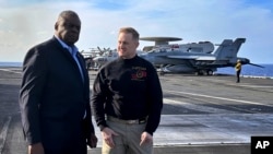 2023年12月20日，国防部长奥斯汀（左）在对该舰突访期间与福特号航空母舰指挥官、海军上校里克·伯吉斯交谈。（美联社照片）