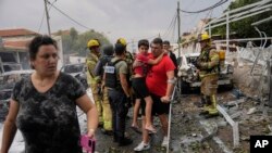 Israelis evacuate a site struck by a rocket fired from the Gaza Strip, in Ashkelon, southern Israel, Oct. 9, 2023.