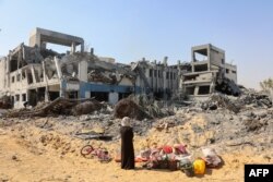 A woman looks around as she salvages items at the damaged U.N. Relief and Works Agency for Palestine Refugees building complex in western Gaza City's al-Sinaa neighborhood, July 12, 2024, following the withdrawal of Israeli troops from the area.