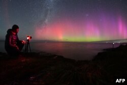 Fotograf snima Auroru Australis, takođe poznatu kao polarna (južna) svjetlost, dok sija na horizontu iznad voda jezera Elsmere na periferiji Krajstčerča, Novi Zeland, 24. aprila 2023.