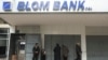 People stand outside a closed branch of Blom Bank in Sidon, Lebanon, Feb. 7, 2023. 