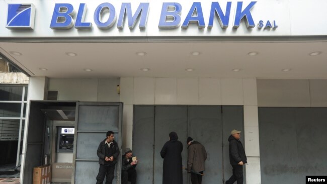 People stand outside a closed branch of Blom Bank in Sidon, Lebanon, Feb. 7, 2023.