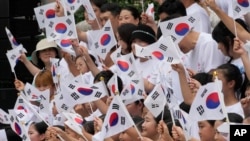 15일 한국 서울 보신각 앞에서 진행된 광복절 행사에서 시민들이 태극기를 흔들고 있다.