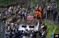 Rescuers remove mud and debris as they search for people feared trapped after a landslide near a temple on the outskirts of Shimla, Himachal Pradesh state, Aug.14, 2023.