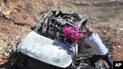 FILE - Samir Ayoub, uncle of three children who were killed by an Israeli airstrike, puts flowers on their car in the town of Ainata, a Lebanese border village with Israel in south Lebanon, Nov. 6, 2023. 
