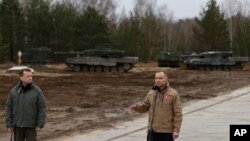 Poland's President Andrzej Duda, right, and Defense Minister Mariusz Blaszczak speak at a press conference at a military base and test range where Ukrainian troops are trained how to operate Leopard 2 tanks, in Swietoszow, Poland, Feb. 13, 2023.