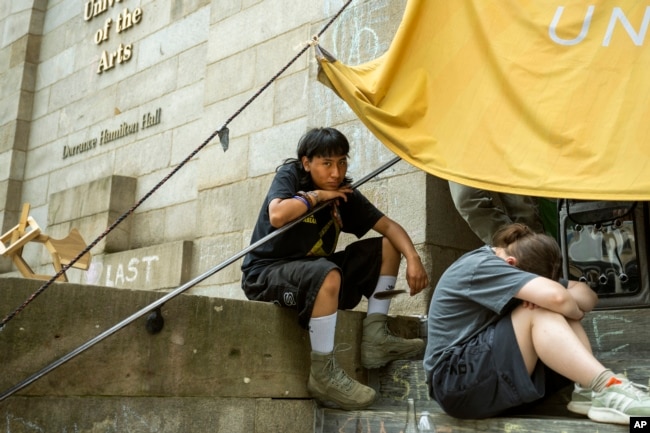 Michael Pacio Ximio, 19, sits on the steps of Dorrance Hamilton Hall at the University of the Arts, Friday, June 14, 2024, in Philadelphia. Students at the university learned recently that their school would be shutting down within days. (AP Photo/Joe Lamberti)