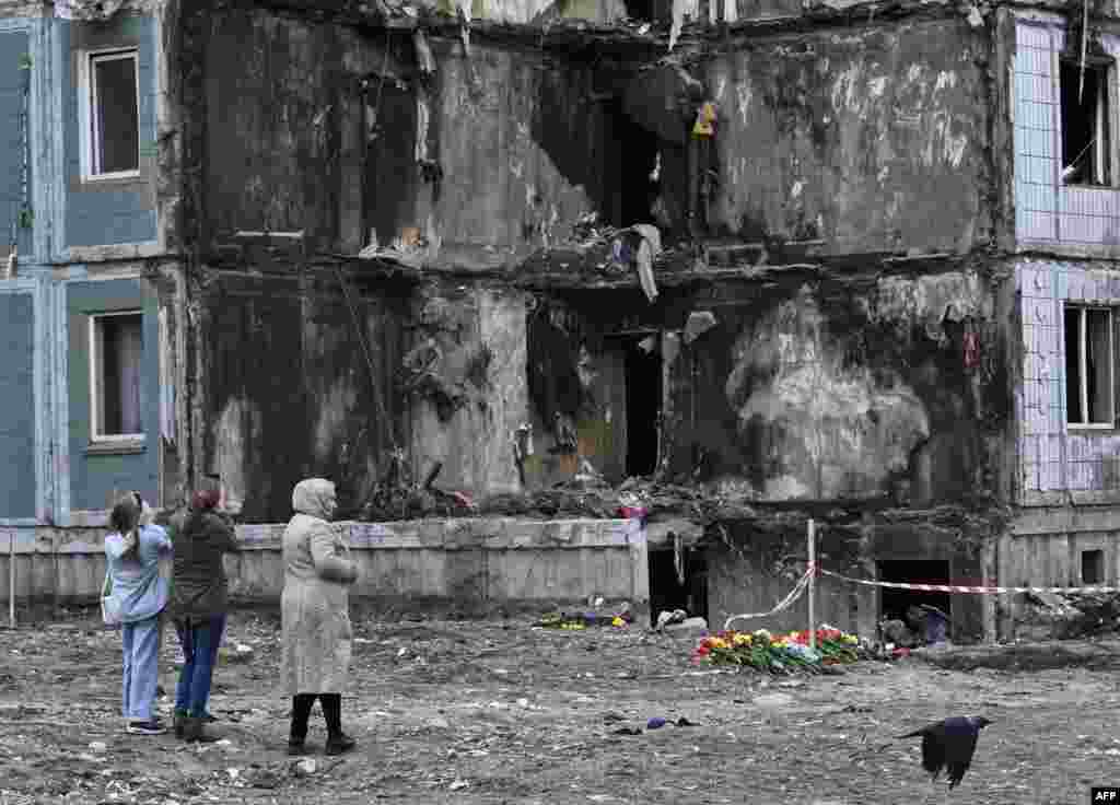 People pay their respects in front of a damaged multi-story residential building, where a Russian strike killed 23 people, in Uman, Cherkasy region.