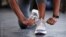 A woman ties up her shoestrings on her sneakers. (Adobe stock image)