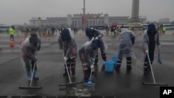 Municipal workers sweeps water off the street near Tiananmen Square in Beijing, China, on March 5, 2024. 