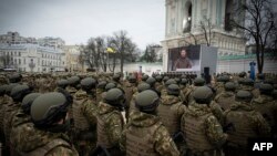 Militares y militares ucranianos asisten a una ceremonia con el presidente ucraniano Volodymyr Zelenskyy en una pantalla en la Plaza de Santa Sofía en Kiev. (Foto tomada y publicada por el servicio de prensa presidencial de Ucrania)