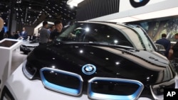 Seorang pekerja membersihkan kendaraan listrik buatan BMW dalam pameran Auto Shanghai 2019 di Shanghai, 17 April 2019. (Foto: Ng Han Guan/AP Photo, arsip)