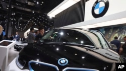 FILE - A worker cleans an electric vehicle at the BMW booth during the Auto Shanghai 2019 show in Shanghai, Apr. 17, 2019. BMW was recalling more than 1.3 million vehicles in China that might have Takata airbag inflators.