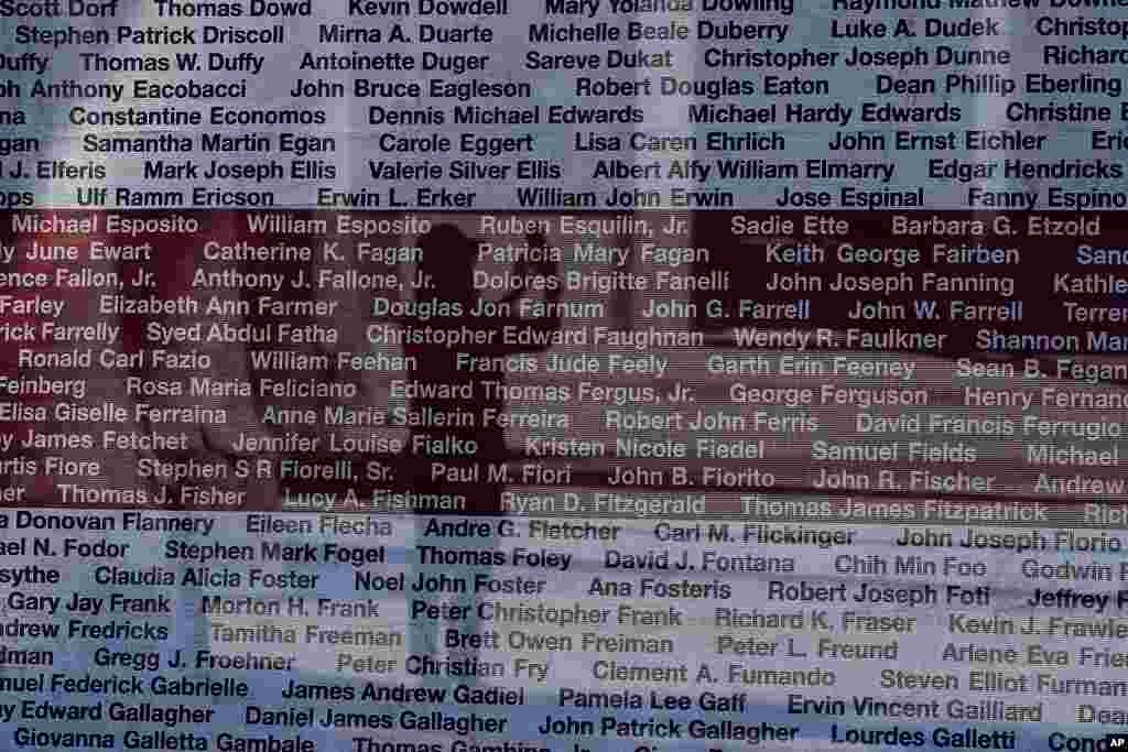 A pedestrian takes photos behind banners showing the names of victims of the Sept. 11, 2001, terrorist attacks, at Willie Mays Plaza outside of Oracle Park in San Francisco.