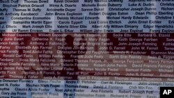 A pedestrian takes photos behind banners showing the names of victims of the Sept. 11, 2001, terrorist attacks, at Willie Mays Plaza outside of Oracle Park in San Francisco.