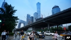 Pedestrians cross an intersection with the background of the central business district in Beijing, July 12, 2024. 