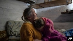 10 year old Khrystyna hugs her grandmother Liubov, 70, as they take cover at the basement of their house during the shelling in Bohoyavlenka, Ukraine, on Sunday, April 9, 2023. Khrystyna's father died last summer after a Russian shell hit his basement. 