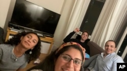 These close work friends, Catalina María Gomez Caycedo (foreground), Aleena Rupani, Henry Crabtree, and Michael Watkins meet in Crabtree's London apartment. (Photo provided by Catalina María Gomez Caycedo via AP)