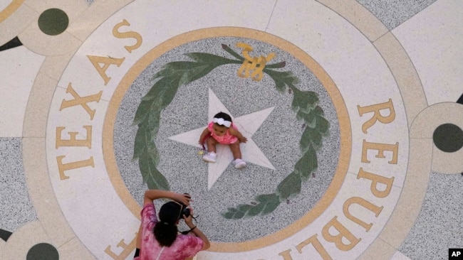 Michaela Herrera toma fotografías de su hija de ocho meses, Jayzaiyah, en el Capitolio de Texas el 6 de mayo de 2021. Más del 49% de los texanos menores de 18 años son hispanos, según estimaciones del censo reciente.