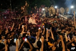 FILE - Supporters throw rose petals toward a vehicle carrying Pakistan's former Prime Minister Imran Khan to greet him upon his arrival at his home in Lahore, Pakistan, May 13, 2023.