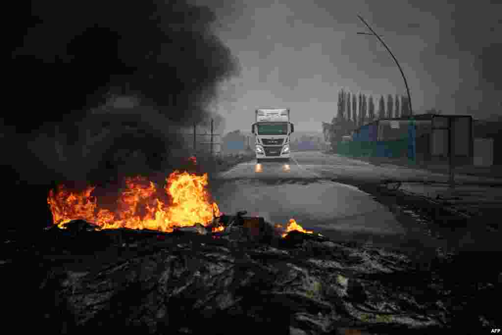 A truck drives towards a fire during a blockade as part of the movement against the government&#39;s proposed pensions reform on the Radicatel Terminal of the harbor in Port Jerome sur Seine, near Rouen, France.