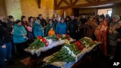 Familiares y amigos de la familia asisten al funeral de Sofia Shulha, de 11 años, y Kyrylo Pysarev, de 17, en Uman, Ucrania, el 30 de abril de 2023. Ambos murieron durante un ataque ruso a un edificio residencial la madrugada del viernes.