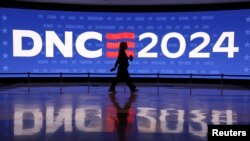 Seorang peserta berjalan melewati layar di United Center, menjelang Konvensi Nasional Demokrat (DNC) di Chicago, Illinois, AS, 19 Agustus 2024. (Kevin Wurm/REUTERS)