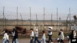 資料照片:2023年3月24日，人們經過靠近北韓邊境的韓國坡州市臨津閣的鐵絲網。