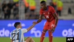 Pesepak bola Panama Gilberto Hernández (kanan) membantu pemain Argentina Paulo Dybala untuk bangkit dalam pertandingan persahabatan antara Panama melawan Argentina di Buenos Aires, pada 23 Maret 2023. (Foto: AFP/Juan Mabromata)