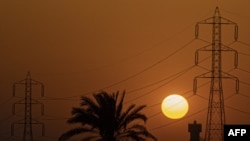 FILE - The sun sets behind high voltage transmission towers (electricity pylons) in Egypt's Qalyubia governorate of the Nile Delta, on June 26, 2022.