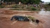 Des personnes regardent un 4x4 submergé par les eaux de crue à Bamako le 29 août 2013. 