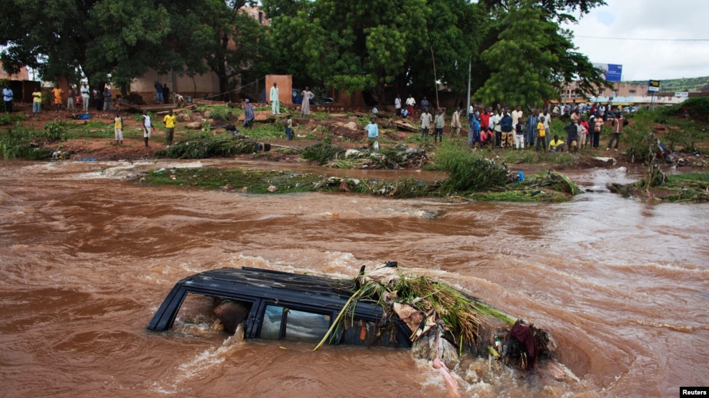 Des personnes regardent un 4x4 submergé par les eaux de crue à Bamako en 2013. 