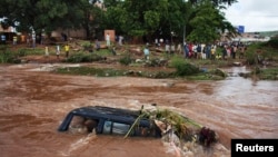 Des personnes regardent un 4x4 submergé par les eaux de crue à Bamako en 2013. 