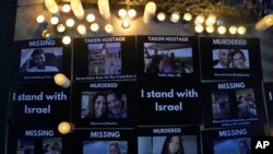 2023年10月9日，在英国伦敦为以色列举行的“犹太社区守夜”期间，死者、传教士和被扣为人质的人的照片放在蜡烛旁边的人行道上。（美联社照片）