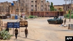 Sudanese Army soldiers walk near armored vehicles positioned on a street in southern Khartoum, May 6, 2023, amid ongoing fighting between the Army and the paramilitary Rapid Support Forces.
