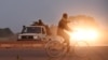 Un homme chevauche des gendarmes alors qu'ils gardent la route menant à la caserne militaire de la garde présidentielle d'élite (RSP), le 29 septembre 2015 à Ouagadougou.