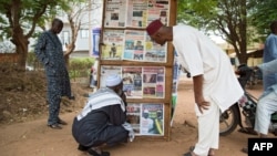FILE - Men look at news headlines of various newspapers in Bamako on June 11, 2021.
