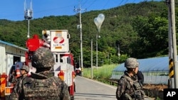 29일 한국 무주에서 북한이 보낸 것으로 추정되는 쓰레기가 담긴 풍선이 전선에 매달려 있는 가운데 병사들이 경비를 서고 있다.