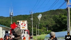 지난달 29일 한국 무주에서 북한이 보낸 것으로 추정되는 쓰레기가 담긴 풍선이 전선에 매달려 있는 가운데 병사들이 경비를 서고 있다.