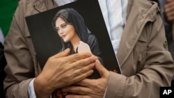 FILE - A person holds a portrait of Mahsa Amini during a rally in Washington on Oct. 1, 2022. Protesters called for regime change in Iran following the death of Amini, a woman who died in custody in Tehran. News reports say Amini's uncle was arrested on Sept. 5, 2023.