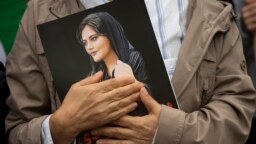 FILE - A person holds a portrait of Mahsa Amini during a rally in Washington on Oct. 1, 2022. Protesters called for regime change in Iran following the death of Amini, a woman who died in custody in Tehran. News reports say Amini's uncle was arrested on Sept. 5, 2023.