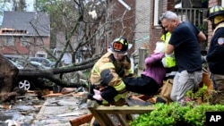 Firefighters carry a woman out of a condo after her complex was damaged by a tornado, March 31, 2023 in Little Rock, Ark. Tornadoes damaged homes, vehicles and uprooted trees.