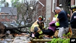 Firefighters carry a woman out of a condo after her complex was damaged by a tornado, March 31, 2023 in Little Rock, Ark. Tornadoes damaged homes, vehicles and uprooted trees.