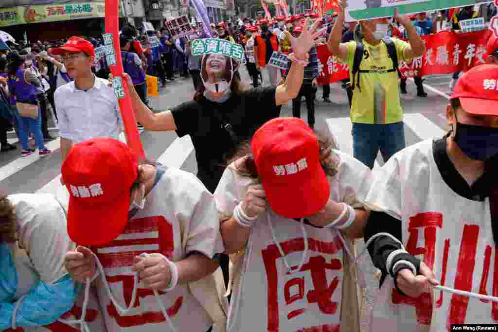 Uma pessoa usa uma máscara com uma impressão do rosto da presidente de Taiwan, Tsai Ing-wen, pedindo que ela responda às reformas da legislação trabalhista durante a marcha anual do Dia do Trabalhador em Taipei, Taiwan, 1º de maio de 2023