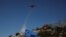 A plane drops water as firefighters try to extinguish a wildfire near the town of Koropi, Greece, June 19, 2024.