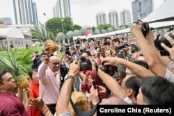 Kandidat presiden Tharman Shanmugaratnam, memegang nanas yang akan menjadi simbol kampanyenya, di Singapura, 22 Agustus 2023. (Foto: REUTERS/Caroline Chia)