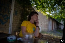 Olena Kanivets smokes a cigarette outside her home in Kupiansk-Vuzlovyi, Ukraine, Aug. 23, 2023.