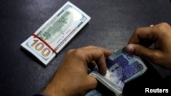 Petugas penukaran uang tampak menghitung lembaran uang rupee Pakistan yang akan ditukarkan dengan dollar AS di sebuah kios penukaran uang di Islamabad, Pakistan, pada 11 Desember 2017. (Foto: Reuters/Caren Firouz)