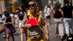 FILE - A woman fans herself in Madrid, Spain, July 10, 2023. 